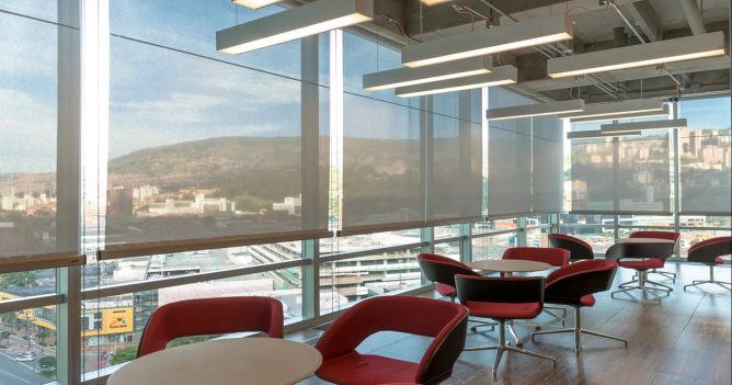 Oficina con ventanales y cortinas para control de iluminación laboral